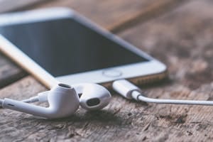 A close-up image of a smartphone and earphones lying on a wooden surface, capturing a moment of connectivity and technology.