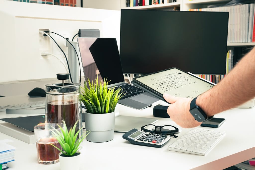 A contemporary office setup featuring technology and greenery on a desk.
